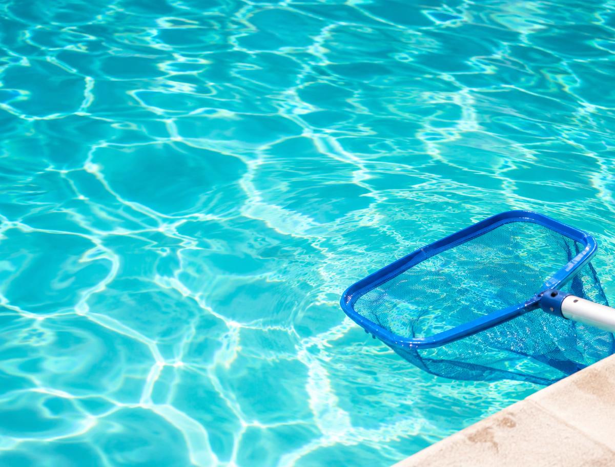 Peneira de limpeza sobre a água turquesa cristalina de uma piscina
