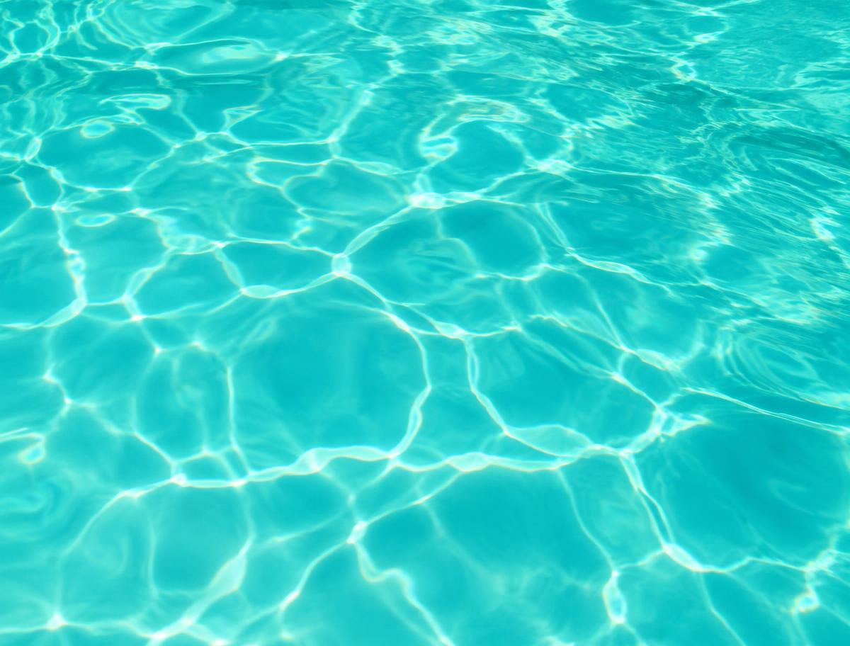 Detalhe da água turquesa de uma piscina sob o sol
